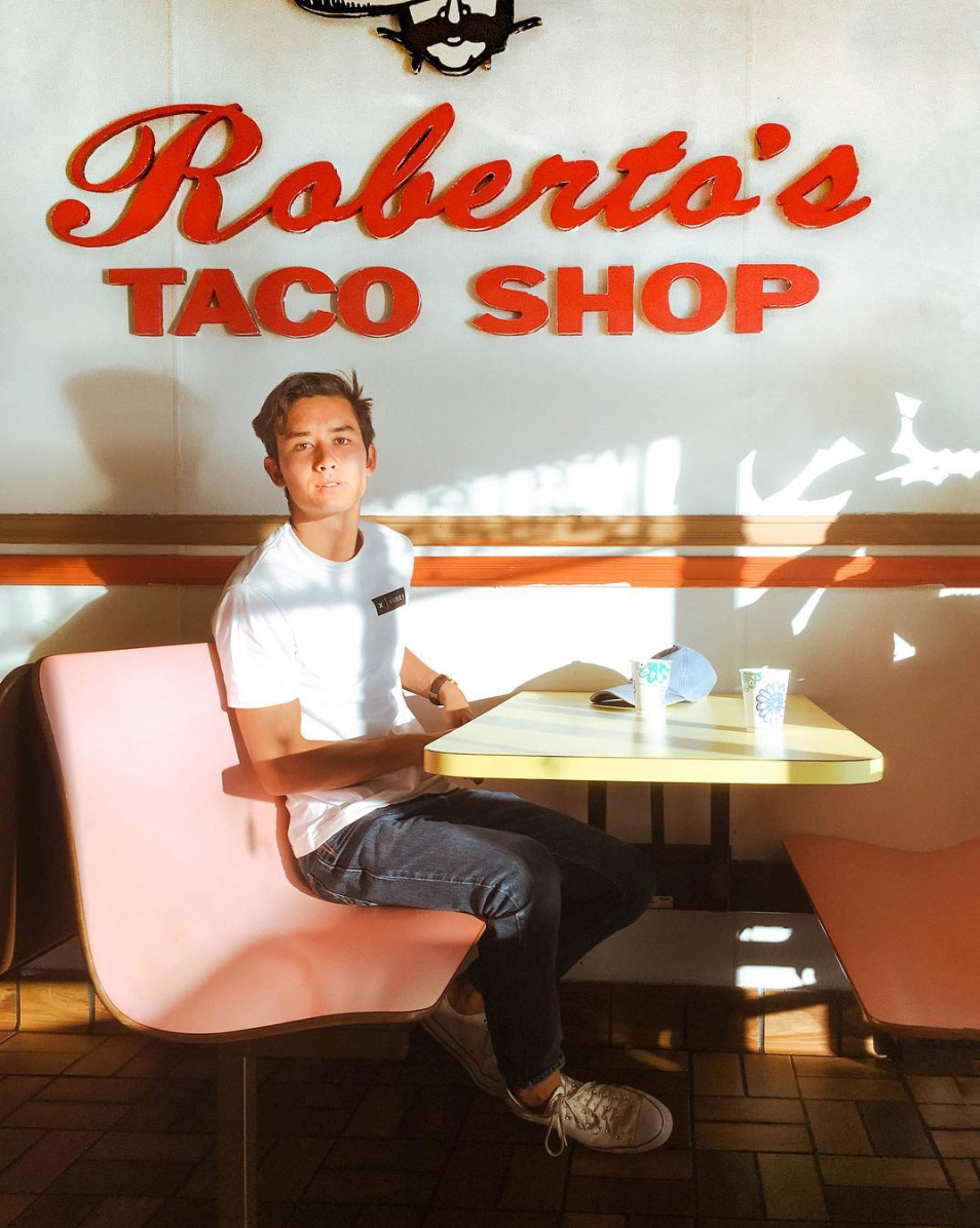 A picture I took of my boyfriend, Alex, at Roberto's, featuring their iconic sign